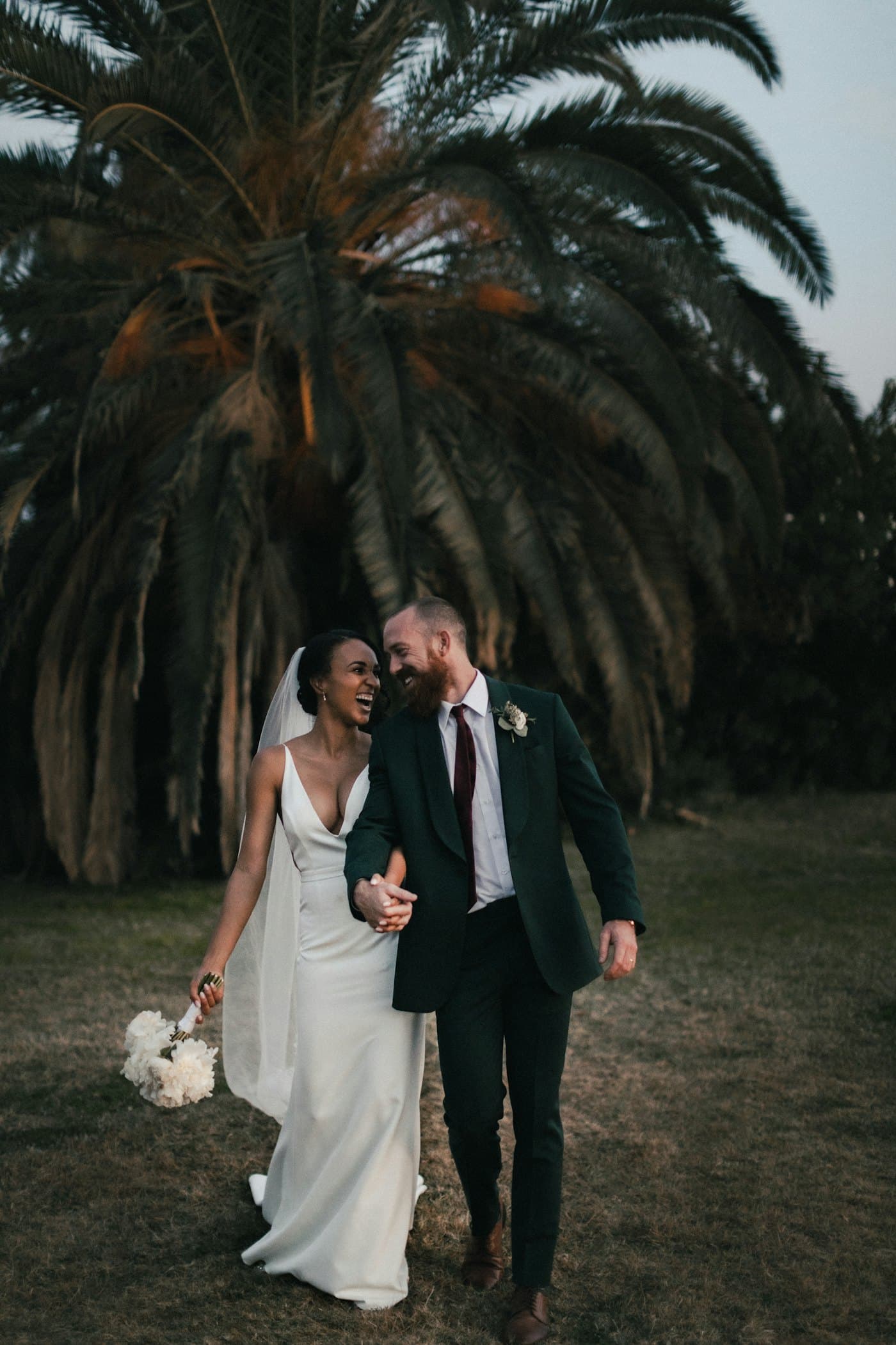 A couple walking under a palm tree